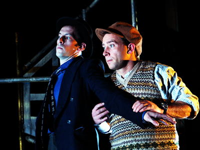 Waist up shot of Denis next to Francois with his arm Outstretched across Francois body, preventing him from moving