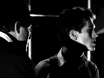 Black and White head and shoulder shot of young Jacques and Philippe in a trilby, with deep shadows falling across parts of their faces