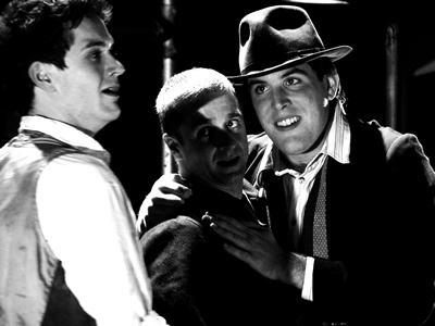 Black and white shot of young Jacques in profile on left facing Philippe with his arm around Denis on right