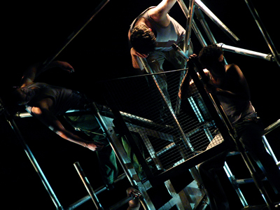 Perspective on the scaffolded block with bars leaning to left and three bodies hanging within it.